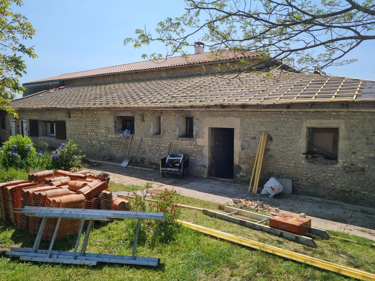 Rustic stone house under renovation with construction materials and scaffolding