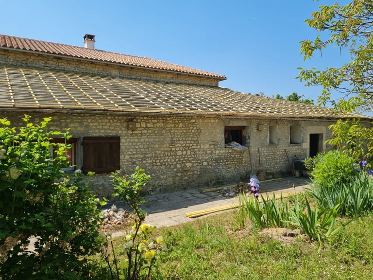 Rustic stone farmhouse with terracotta tile roof and surrounding garden