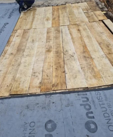 Wooden floor planks laid out diagonally on underlayment during installation, showing natural wood grain and color variations